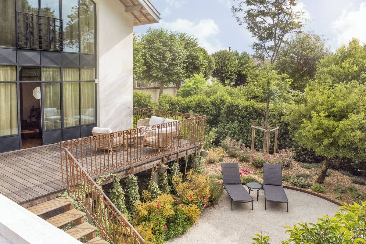 Une maison moderne dotée d’une terrasse en bois, d’un espace salon extérieur et d’un jardin.
