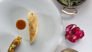 Un plato blanco con un pastel, un tazón pequeño de salsa y un recipiente metálico con una crema.