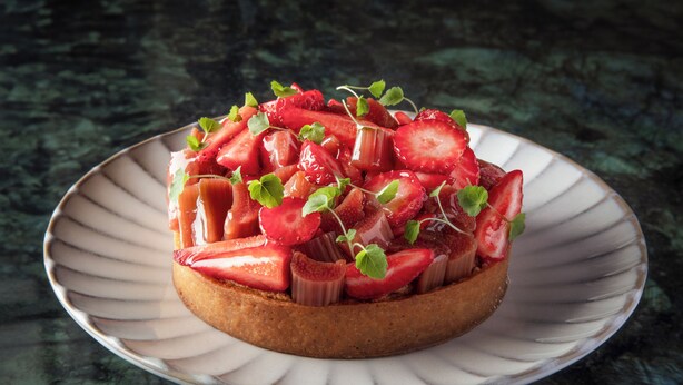 Un dessert servi dans une assiette blanche à bord texturé, posée sur une surface sombre.