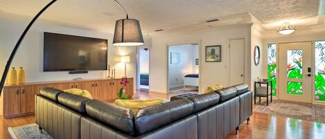 A modern living room with a leather sofa, a flat-screen TV, and a large lamp.