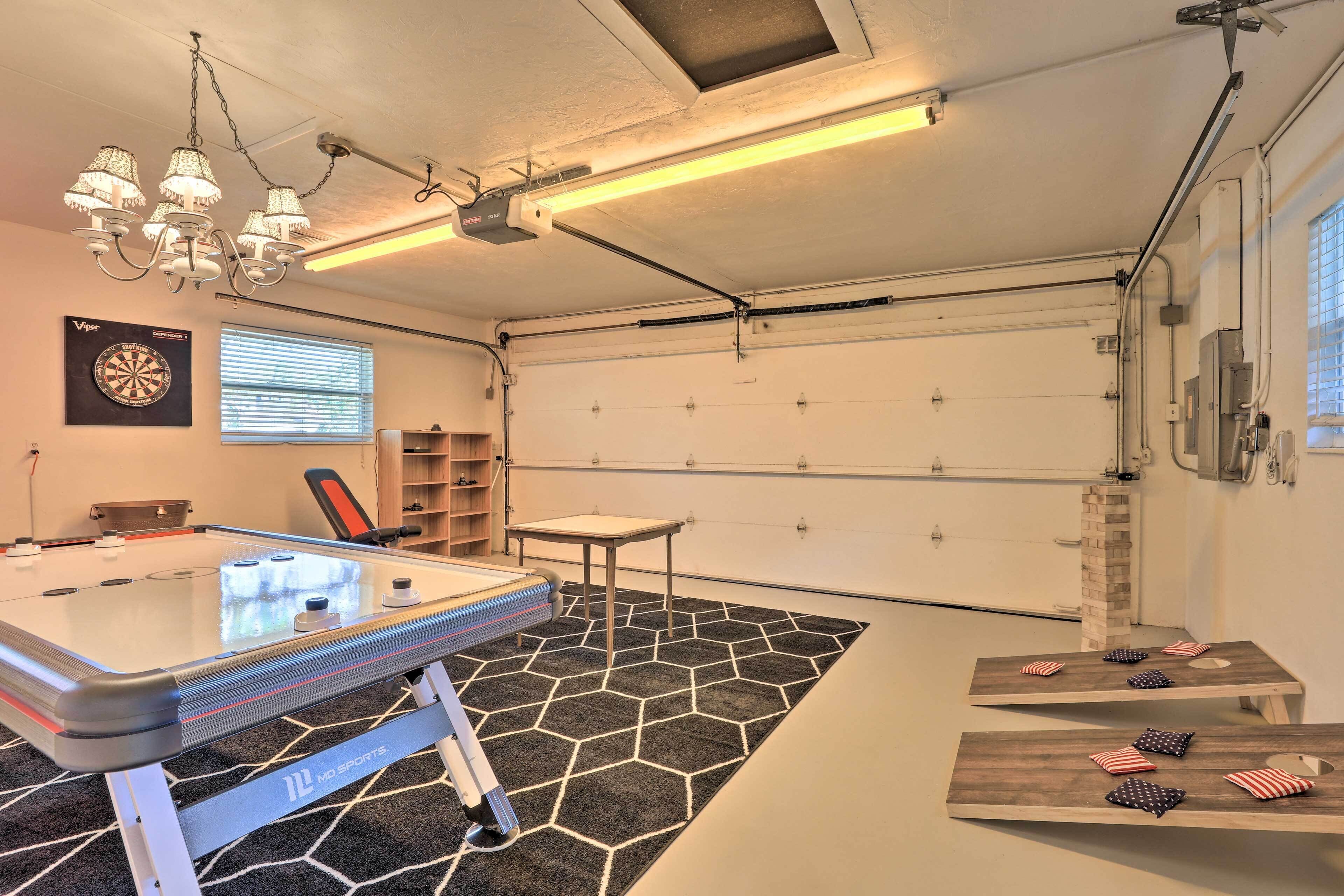 A room with a ping pong table, dartboard, and a small table with American flags.