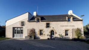Un bâtiment en pierre avec un toit en pente et une allée gravillonnée.