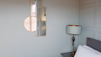 A bedroom with a bed, a nightstand, a lamp, and wall-mounted mirrors.