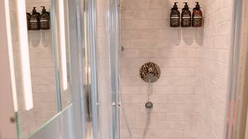 A modern bathroom with a glass-enclosed shower, white tiled walls, and a mirror above the sink.