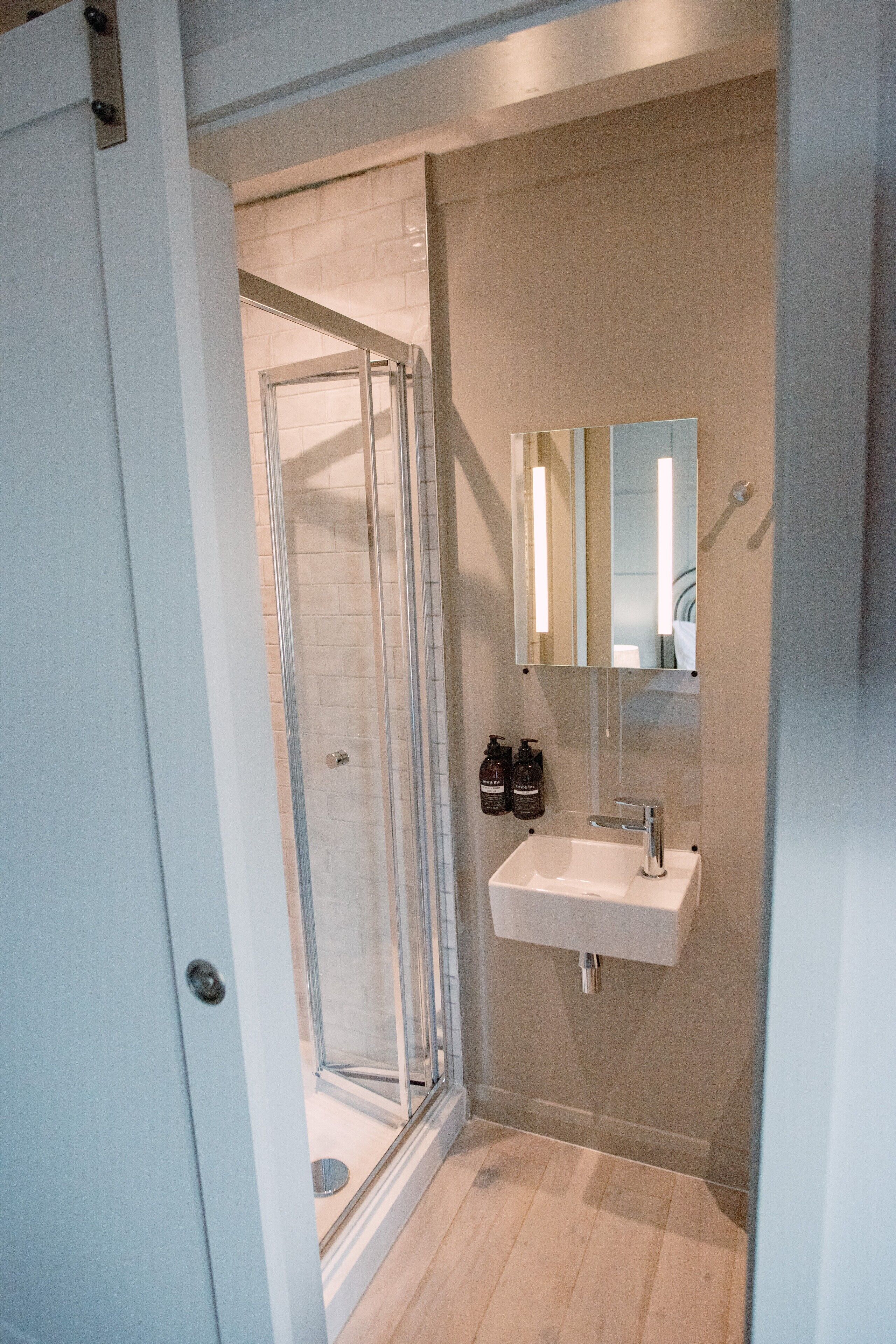 Une salle de bain moderne avec une douche à parois de verre, un lavabo blanc et un miroir au-dessus.