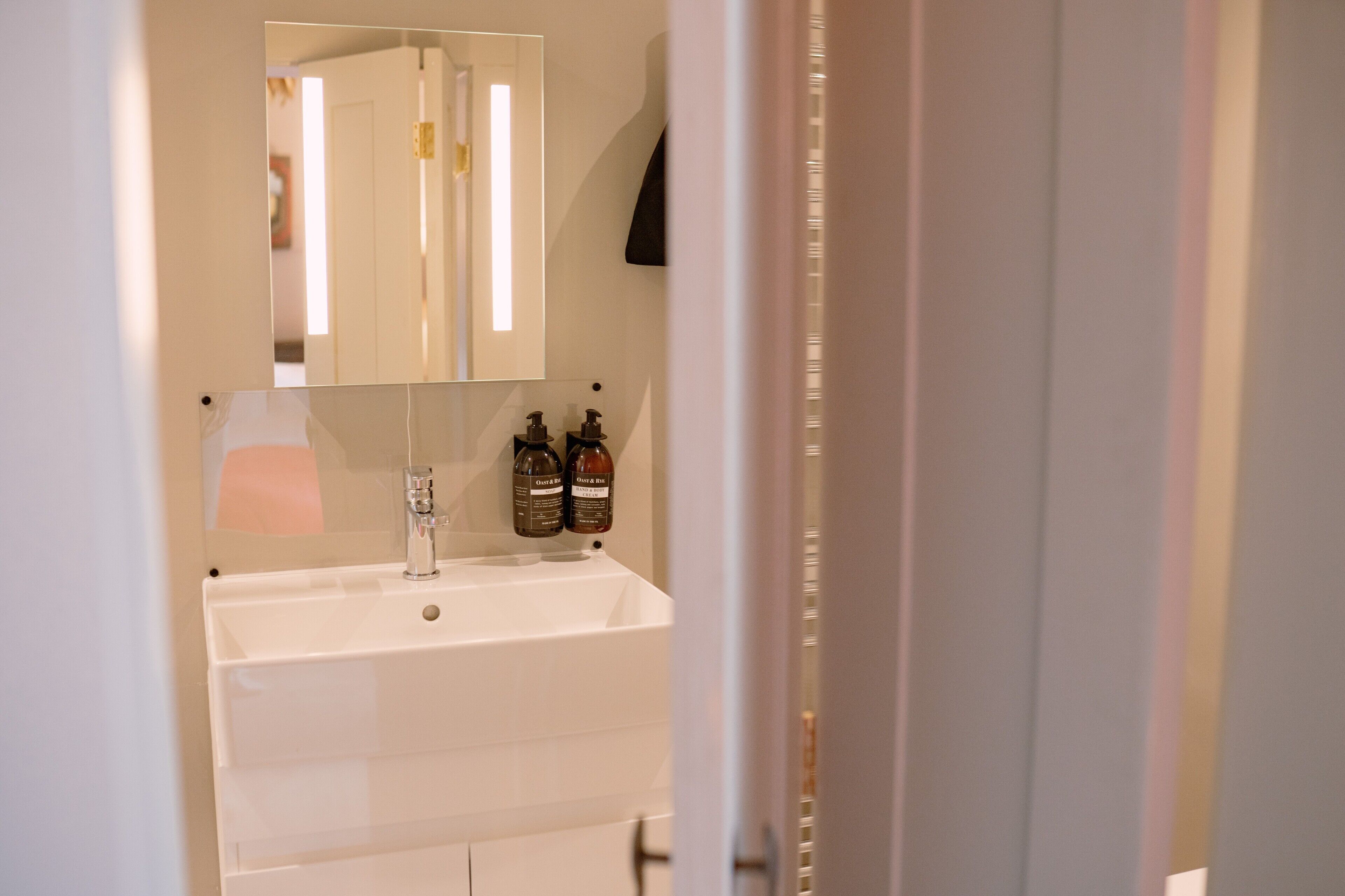 A bathroom with a white sink, a mirror, and two bottles of hand soap.