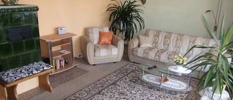 A living room with a green cabinet, a sofa, a chair, a coffee table, and a large plant.