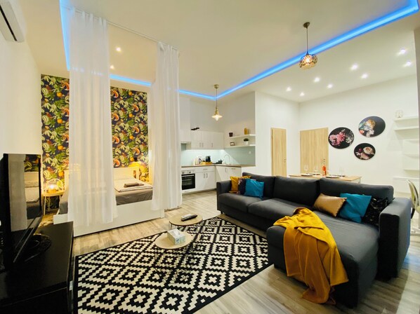 A modern living room with a sofa, coffee table, and a patterned rug. - Chic Luxury Central Studio with A/C - Tropical House (Budapest)