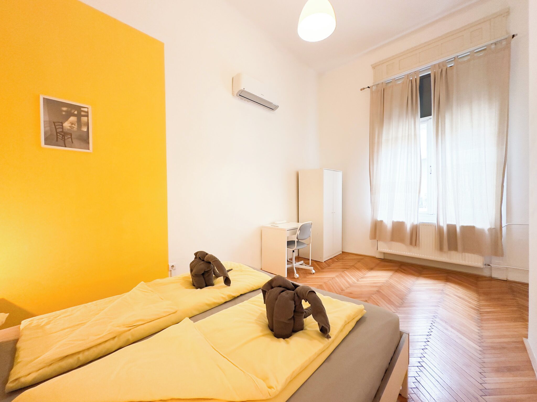 Una habitación con dos camas, un escritorio, un armario y una ventana con cortinas.
