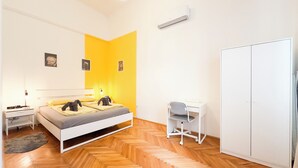 A bedroom with a bed, bedside table, desk, wardrobe, and a herringbone-patterned wooden floor. - Large Peaceful 1BR Central Apt A/C - Yellow House (Budapest)