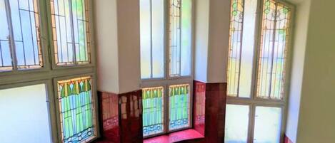 A room with large stained glass windows and a curved bench.