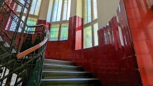 A staircase with a metal handrail, leading to a landing with large windows. - Charming 1BR Condo with A/C in Central Budapest - Skyline House (Budapest)