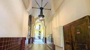 A corridor with tiled walls, a tiled floor, a ceiling light fixture, and a door on the right. - Charming 1BR Condo with A/C in Central Budapest - Skyline House (Budapest)