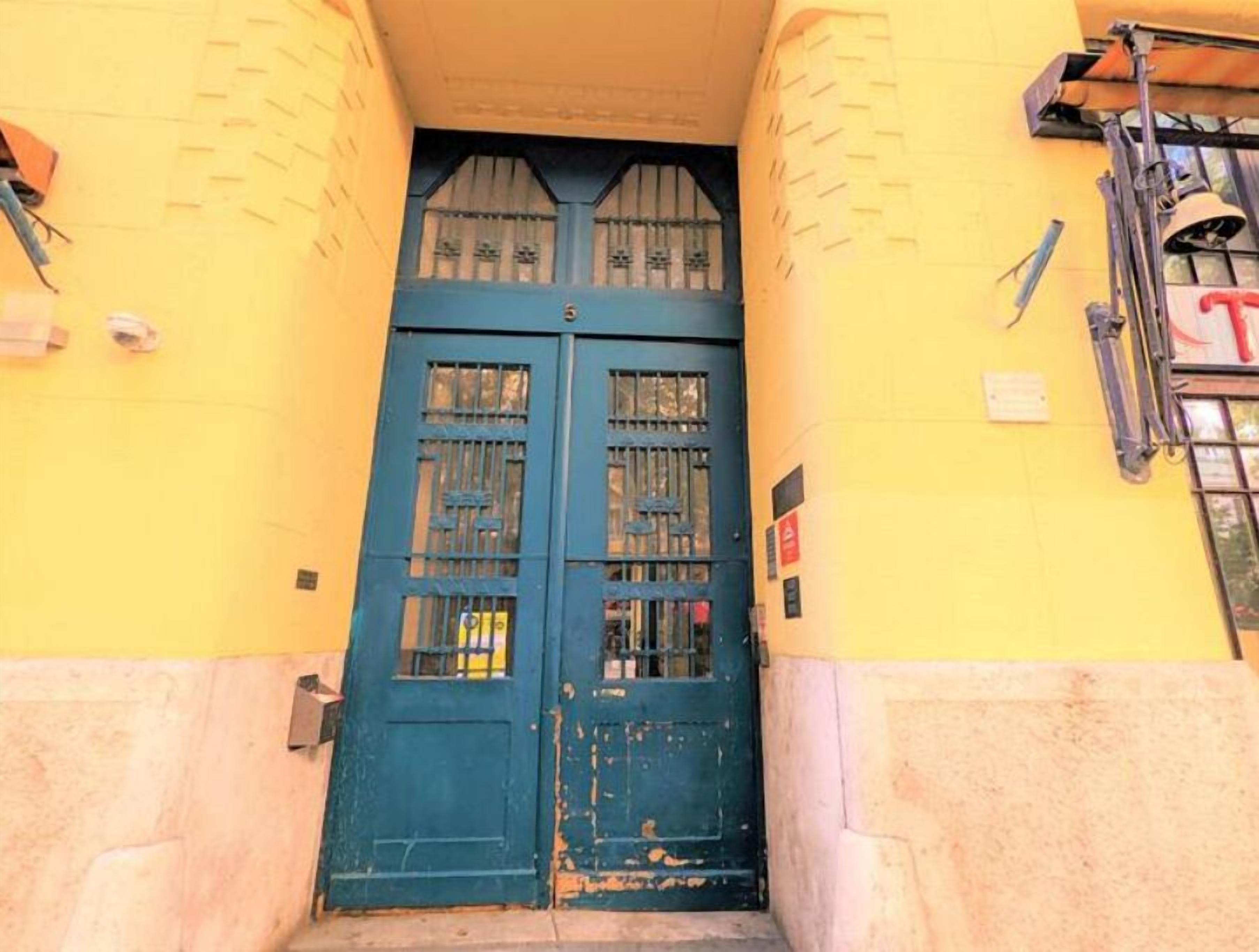 Puertas dobles con ventanas de rejas, integradas en un edificio amarillo con base de piedra.