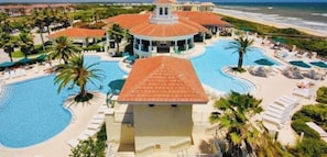 A resort with a central building, multiple swimming pools, and a beach view.