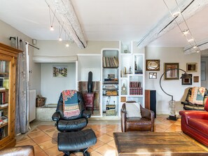 Un salon avec une cheminée, des fauteuils en cuir, une bibliothèque et un canapé rouge.