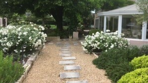A garden pathway leading to a building with a covered patio area.