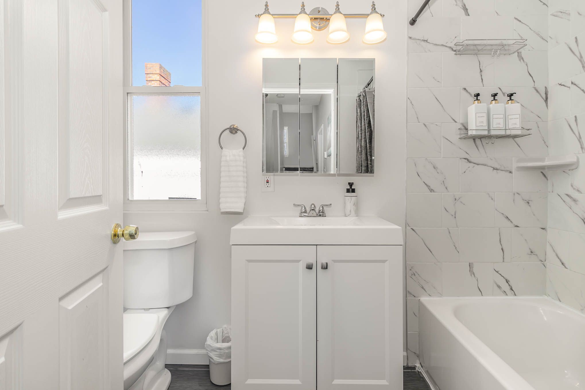 Un baño moderno con inodoro, lavamanos, espejo y bañera.