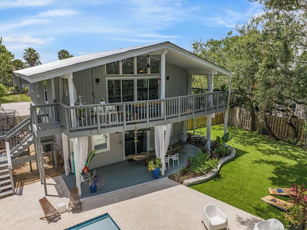 A two-story house with a balcony, a pool, and a well-maintained lawn.