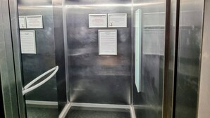 Un ascenseur vide aux parois en acier inoxydable, doté d’une main courante et de panneaux d’information.