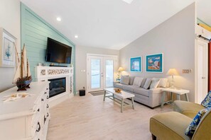 A living room with a fireplace, a sofa, a television, and artwork on the walls.
