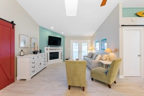 A spacious living area with a fireplace, a television, and a dining table.