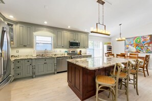 A modern kitchen with a large island, built-in appliances, and a dining area with chairs.