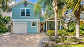 A two-story house with a garage, a covered porch, and a well-maintained garden. - Island Sun House - Walk to State Park and Beach! (St. Augustine)