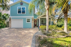 Une maison à deux étages avec un garage, une véranda et un jardin bien entretenu.