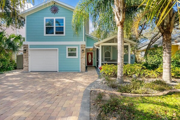 A two-story house with a garage, a covered porch, and a well-maintained garden.