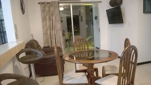 Un coin repas comprenant une table ronde, quatre chaises en bois, un tabouret de bar et un canapé.
