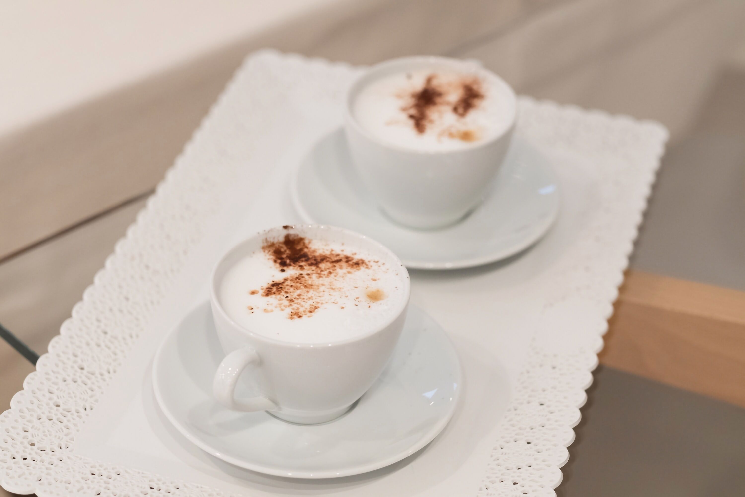 Zwei weiße Kaffeetassen auf einer weißen Tischdecke.