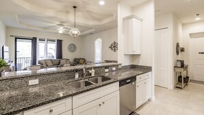 A modern kitchen with granite countertops, stainless steel appliances, and white cabinetry.