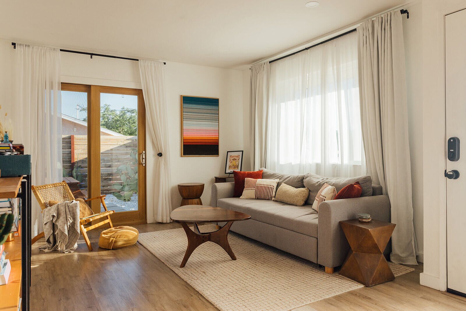 Ett modernt vardagsrum med en soffa, ett soffbord, en fåtölj och ett stort fönster med gardiner.