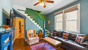 A living room with a staircase, a sofa, a coffee table, and a television.