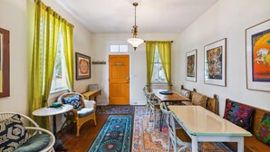 A dining area with a long table and chairs, a small round table with a chair, and a window with curtains.