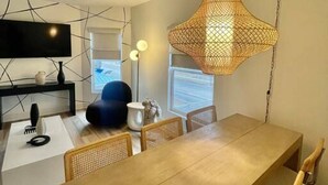 Ein moderner Essbereich mit einem langen Holztisch, Korbstühlen und einer außergewöhnlichen gewebten Pendelleuchte.