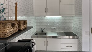 Een kleine keuken met witte kastjes, een roestvrijstalen spoelbak en een aanrecht.