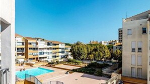 A residential building with a swimming pool, multiple balconies, and a clear sky. - Apartment Center harbor 4p Air-conditioned + Car park CAP6 (Agde)