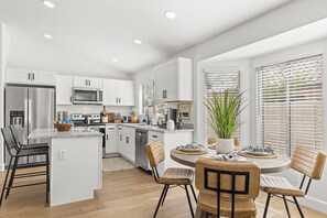 Una cocina moderna con armarios blancos, electrodomésticos de acero inoxidable y una isla central con asientos.