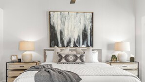 Una camera da letto ordinata con un letto grande, due comodini e un quadro astratto appeso al muro.