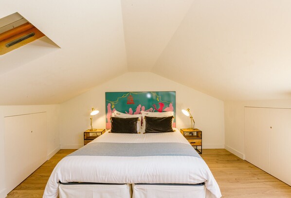 A bedroom with a sloped ceiling, a bed with white bedding, two bedside lamps, and a colorful headboard. - BAIRRO ALTO MUSIC GUEST HOUSE MOZART (Lisboa ciudad)