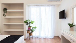 A bedroom with a bed, a TV, a dresser, and a window with sheer curtains. - Acropolis Prestige Residence (Athina)