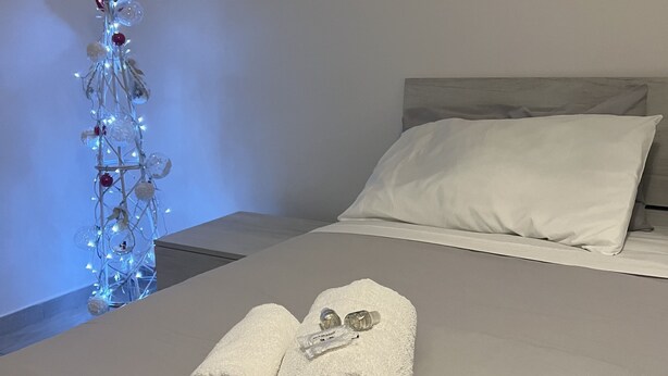 A neatly made bed with white linens, a white pillow, and a folded towel on the bed.