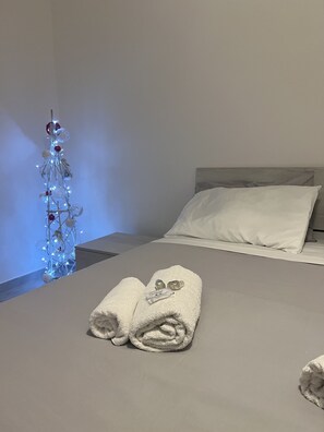 A neatly made bed with white linens, a white pillow, and a folded towel on the bed. - Bignami street monteverde(near Trastevere) (ROMA)
