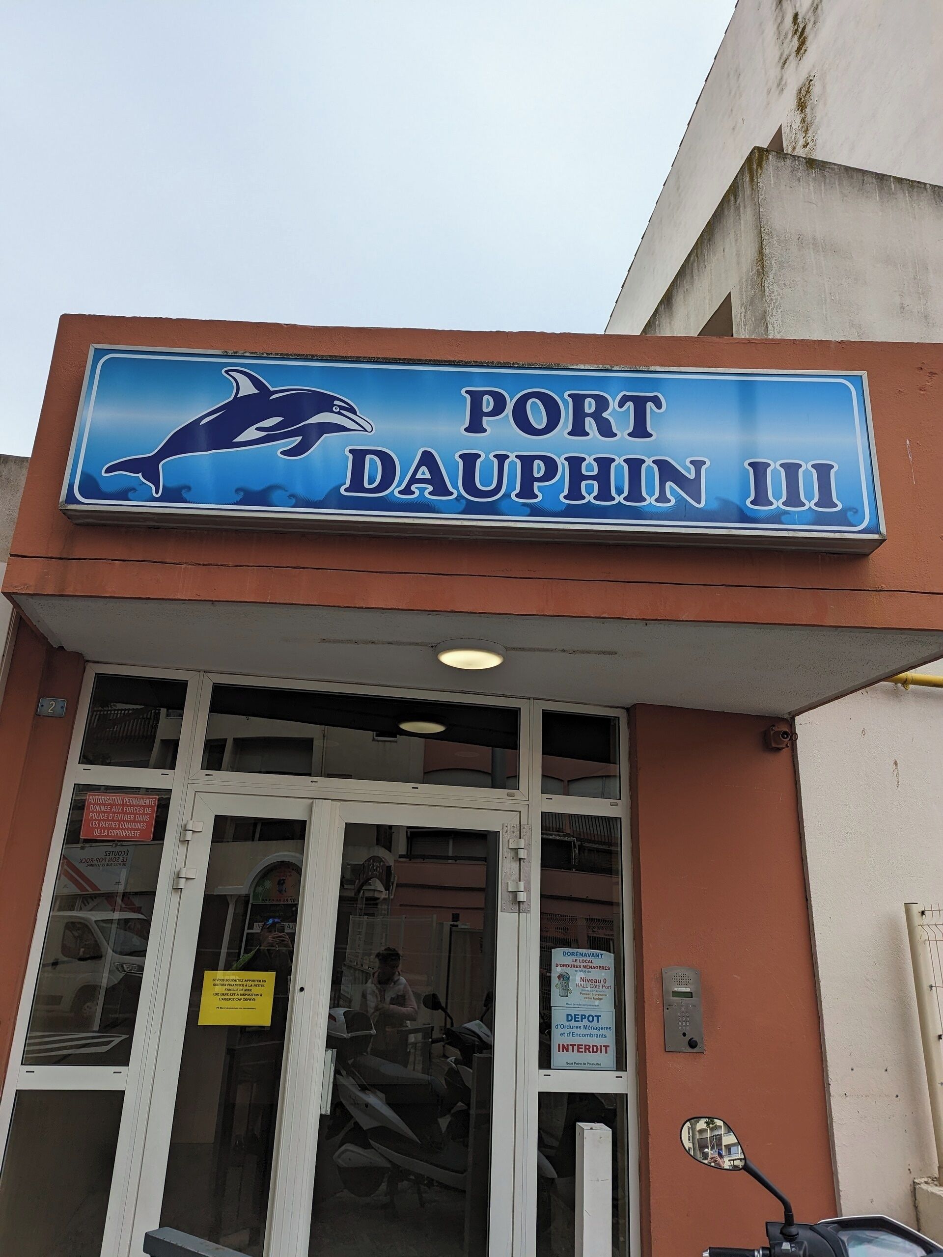 Un bâtiment sur lequel on peut lire l’inscription « Port Dauphin III » et qui arbore un logo représentant un dauphin.
