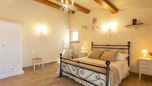 Een slaapkamer met een bed, een stoel, een nachtkastje, een kroonluchter en wandlampen.