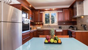 Una cocina moderna con electrodomésticos de acero inoxidable, armarios de madera y una isla central con frutero.