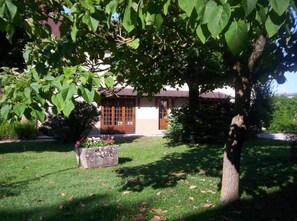 Ein traditionelles Gebäude mit Ziegeldach, umgeben von einem gepflegten Rasen und einem großen Baum.