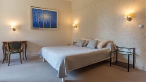 Ein Schlafzimmer mit Bett, Stuhl, Schreibtisch und einem Bild an der Wand.